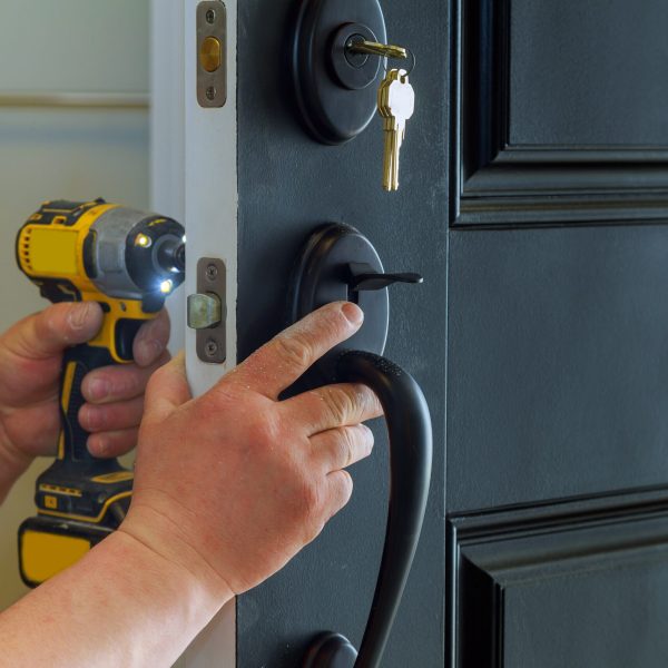 Closeup of a professional locksmith installing a new lock on a house exterior door with the inside internal parts of the lock